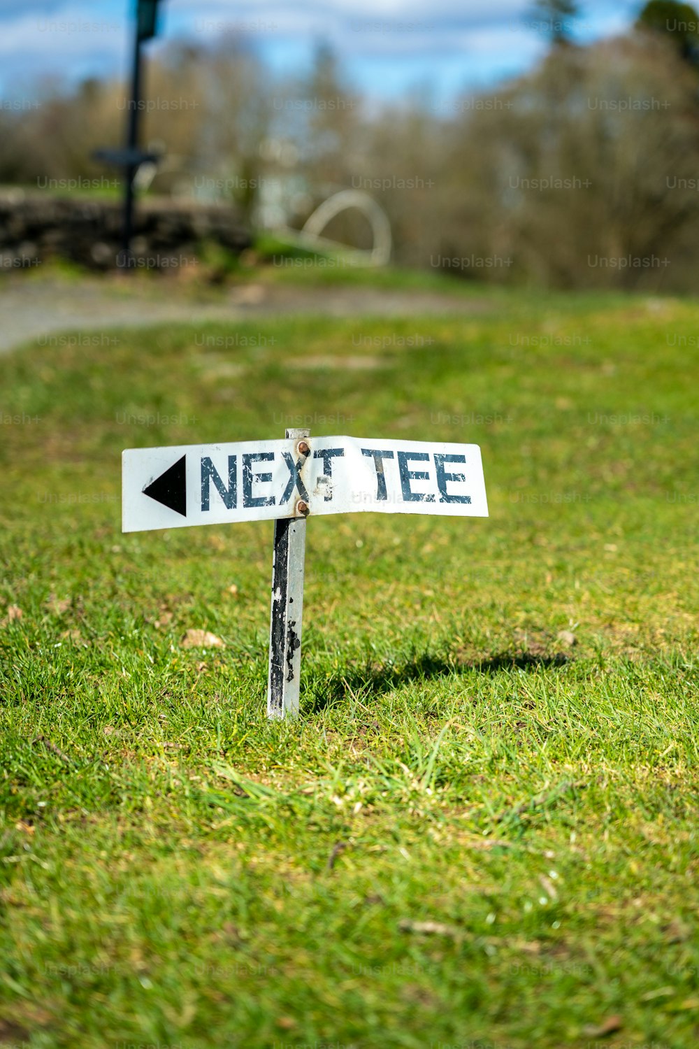 a white street sign sitting on top of a lush green field