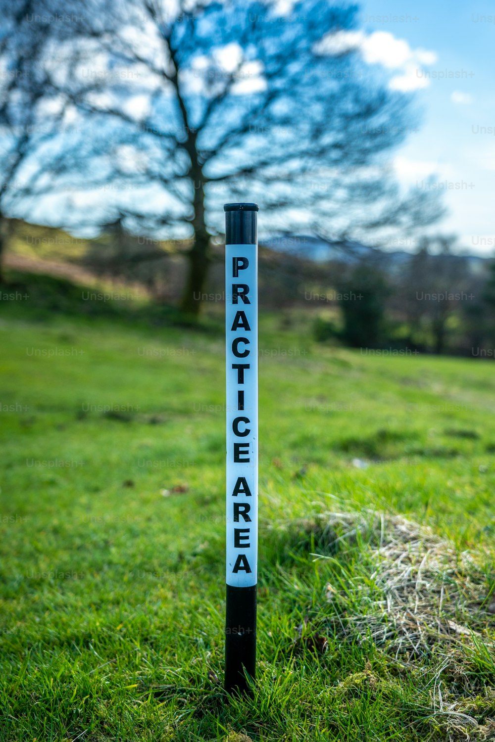 ein Schild, das sich im Gras in der Nähe eines Baumes befindet