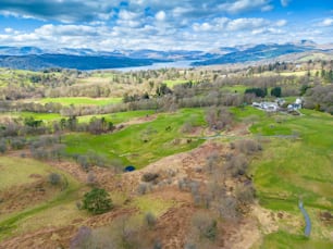 an aerial view of a green field with mountains in the background