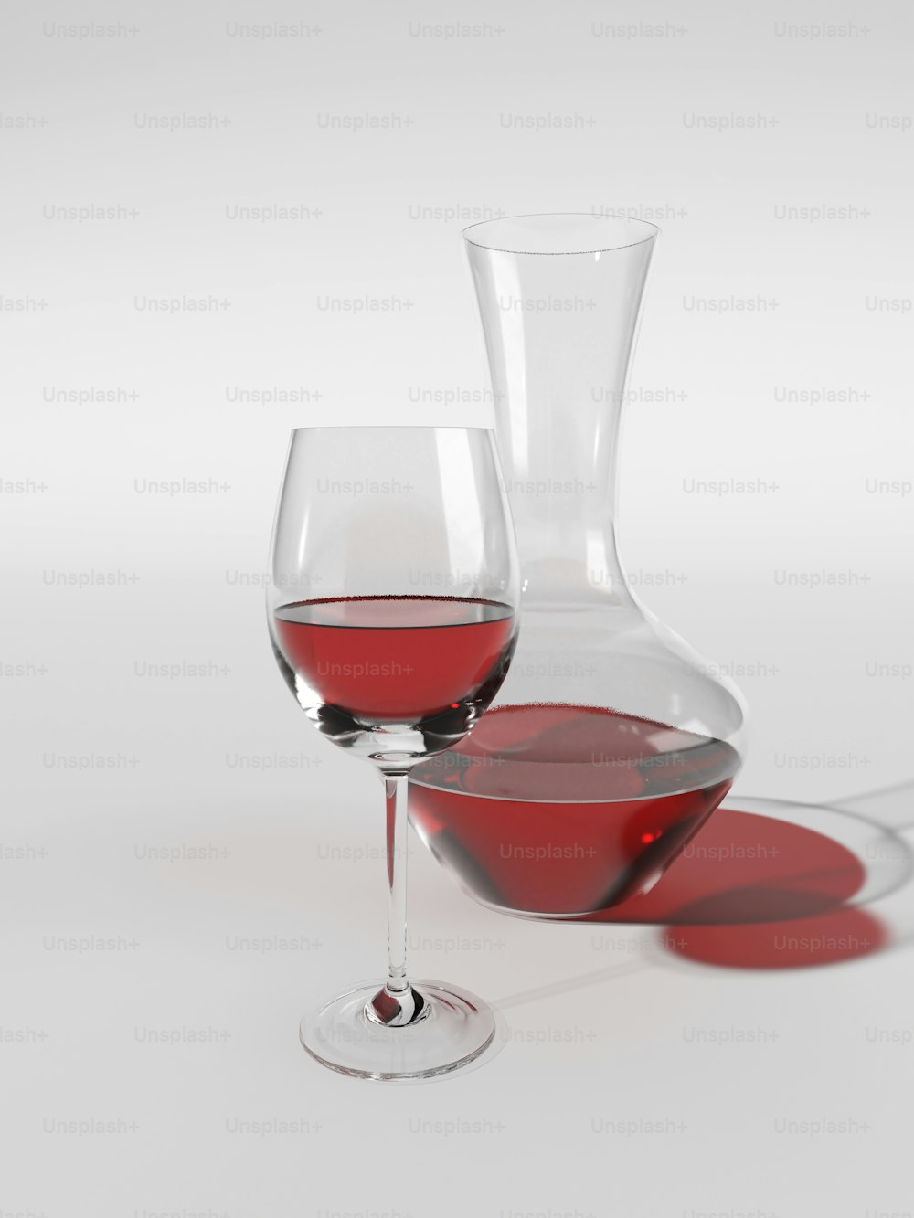 a glass of red wine next to a wine decanter