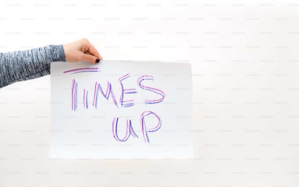 a person holding a piece of paper with the words times up written on it