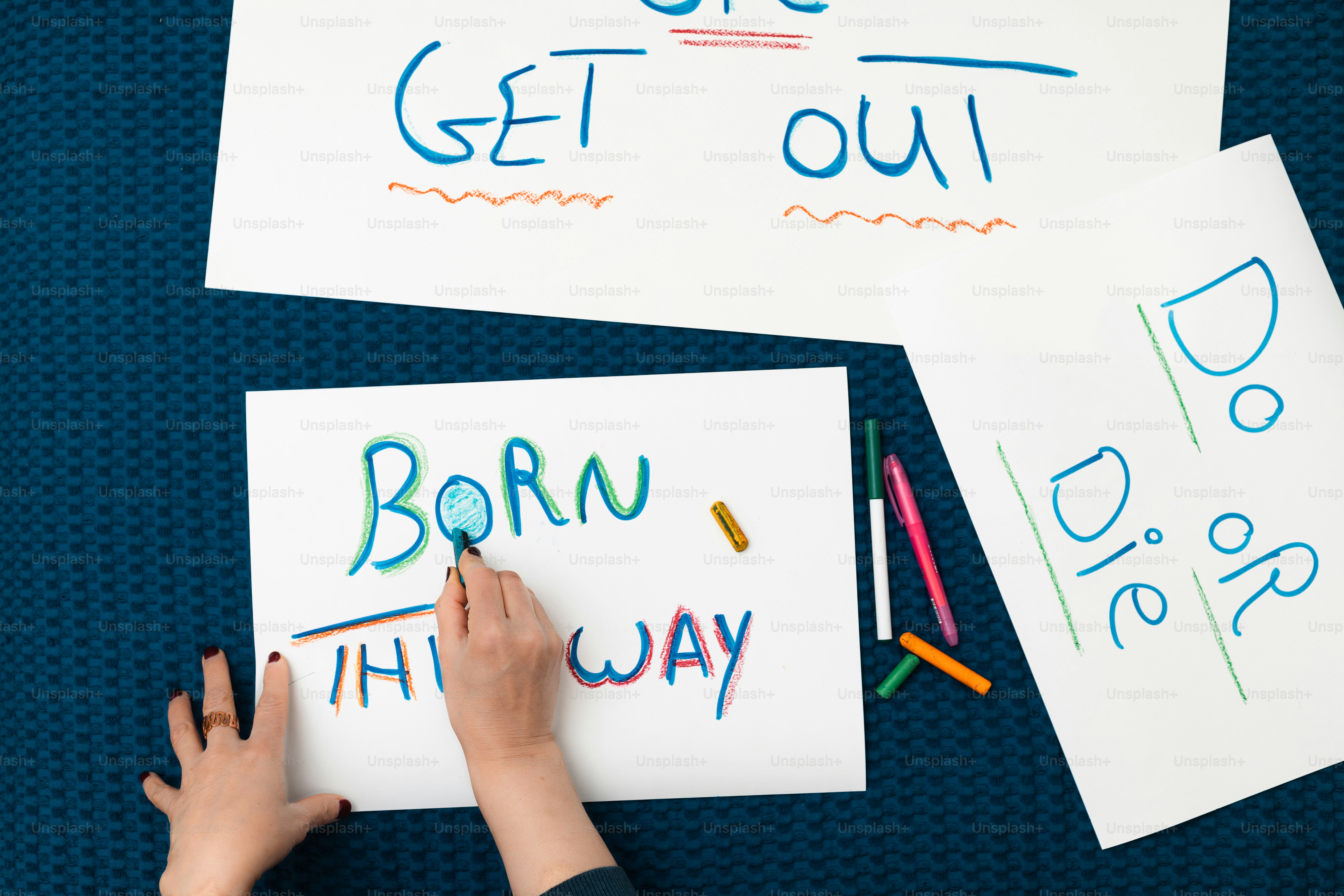 a child's hand writing on paper with colored crayons