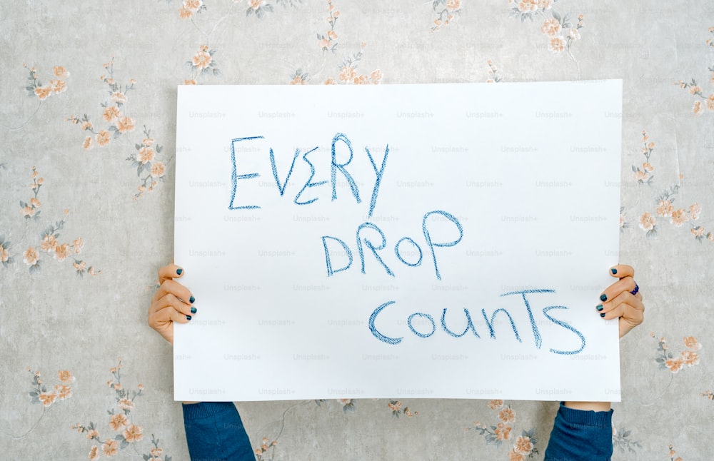 a person holding a sign that says every drop counts