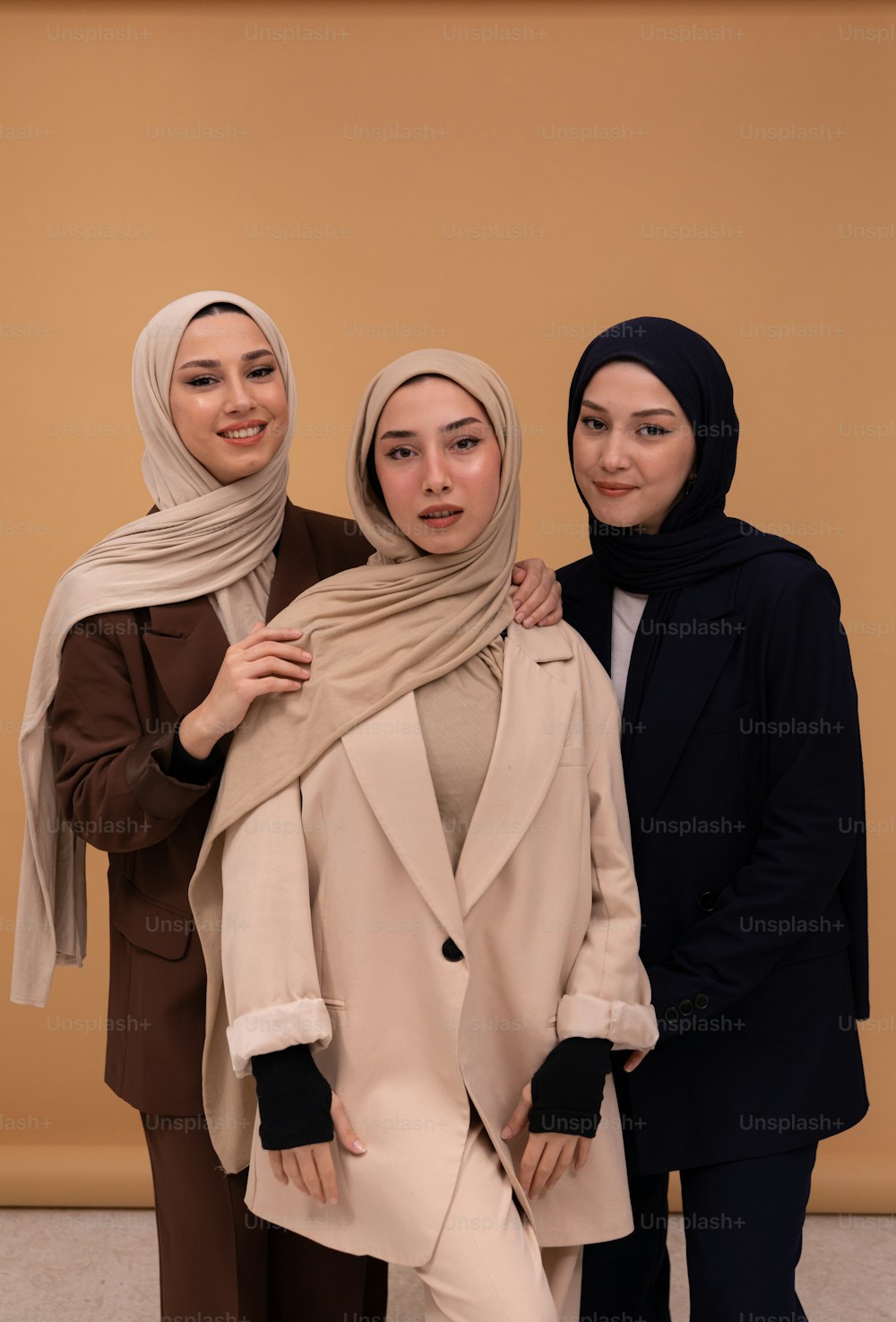 three women standing next to each other in front of a wall