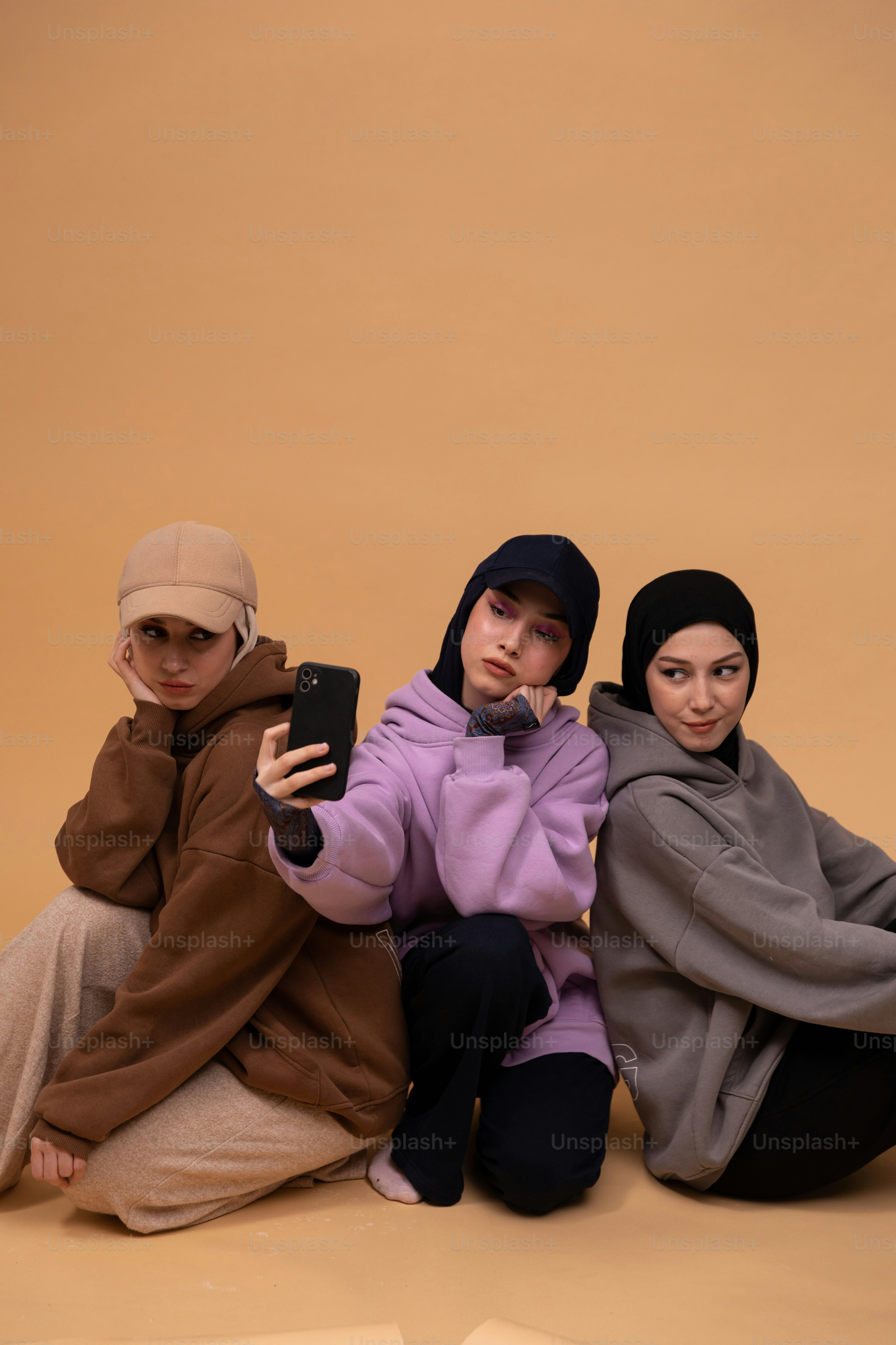 três mulheres sentadas no chão com um telefone celular