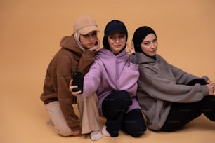 three women sitting on the ground posing for a picture