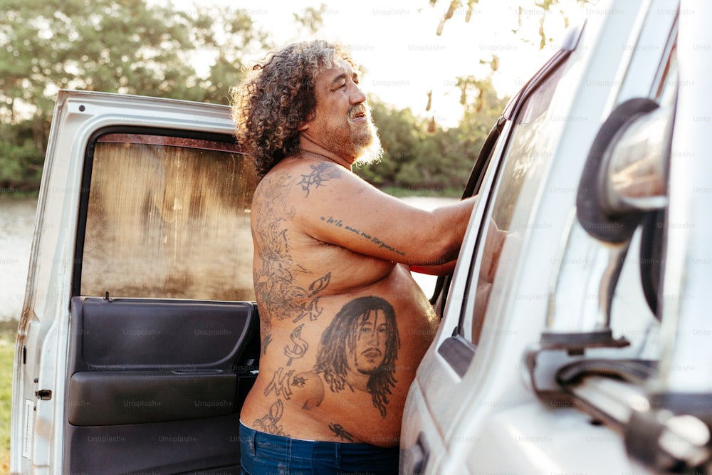 a man with a tattoo standing next to a van