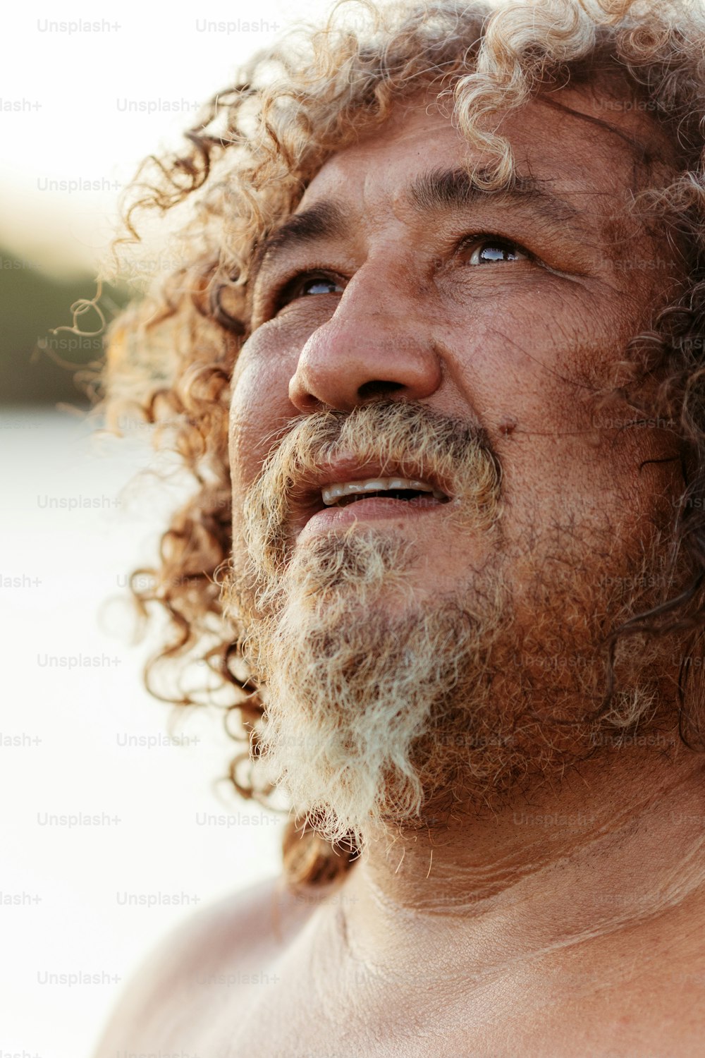um close up de um homem com cabelos encaracolados e barba
