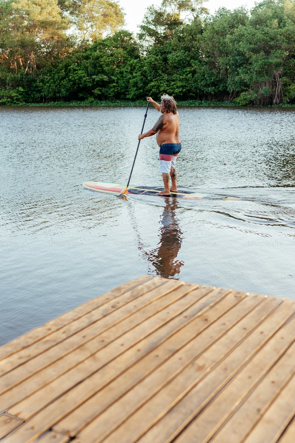 um homem montando uma prancha de remo no topo de um lago