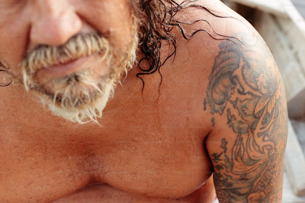 un gros plan d’un homme avec des tatouages sur la poitrine