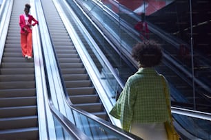 a woman walking down an escalator next to another woman