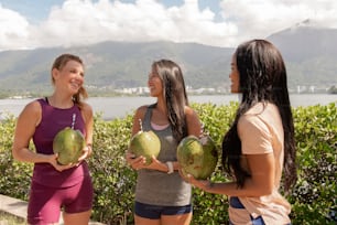 a group of women standing next to each other holding watermelons
