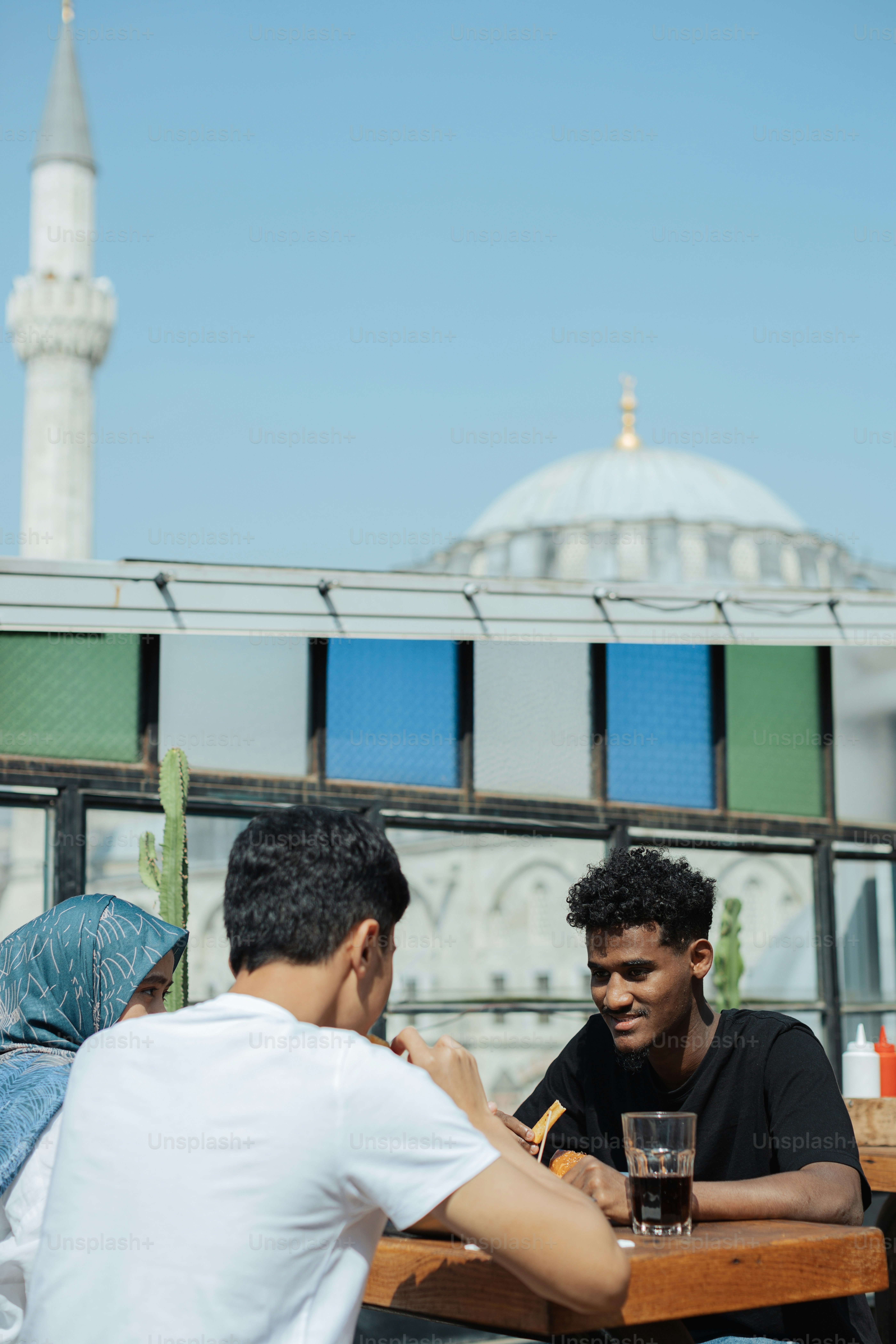 two men are sitting at a table outside