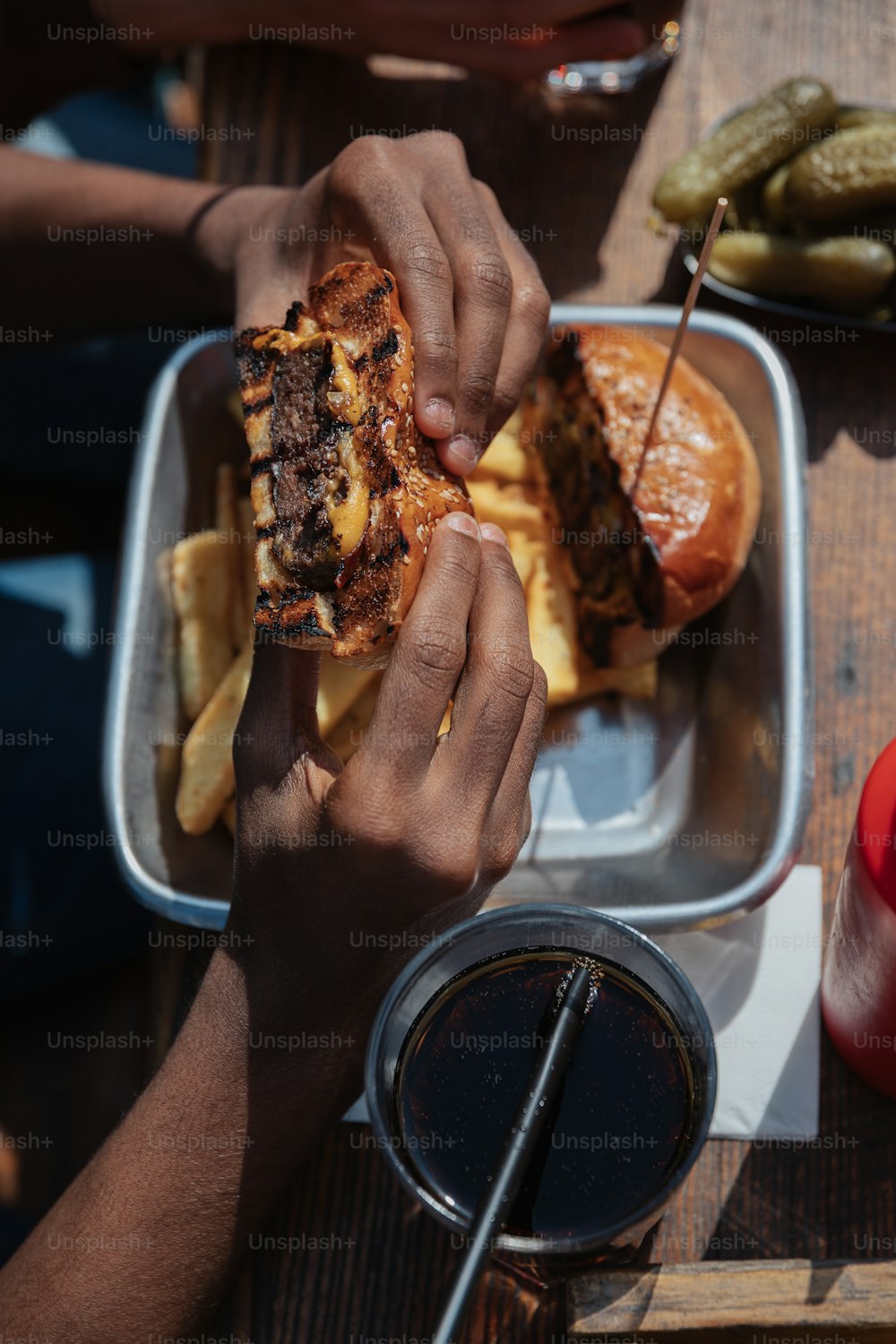 a person holding a sandwich over a plate of food