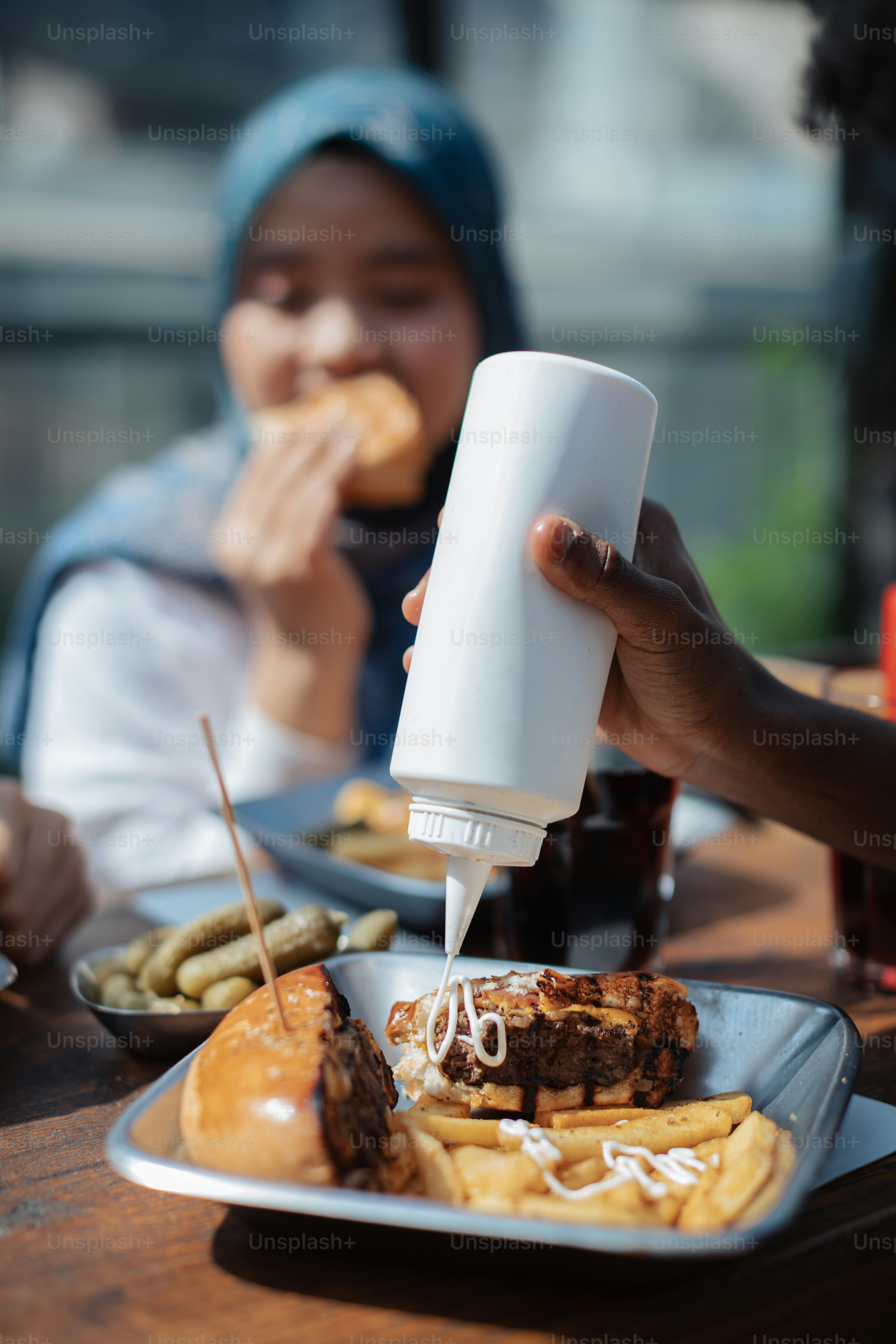 a person pouring sauce on a plate of food