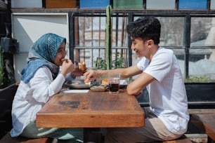 a man and a woman sitting at a table eating food