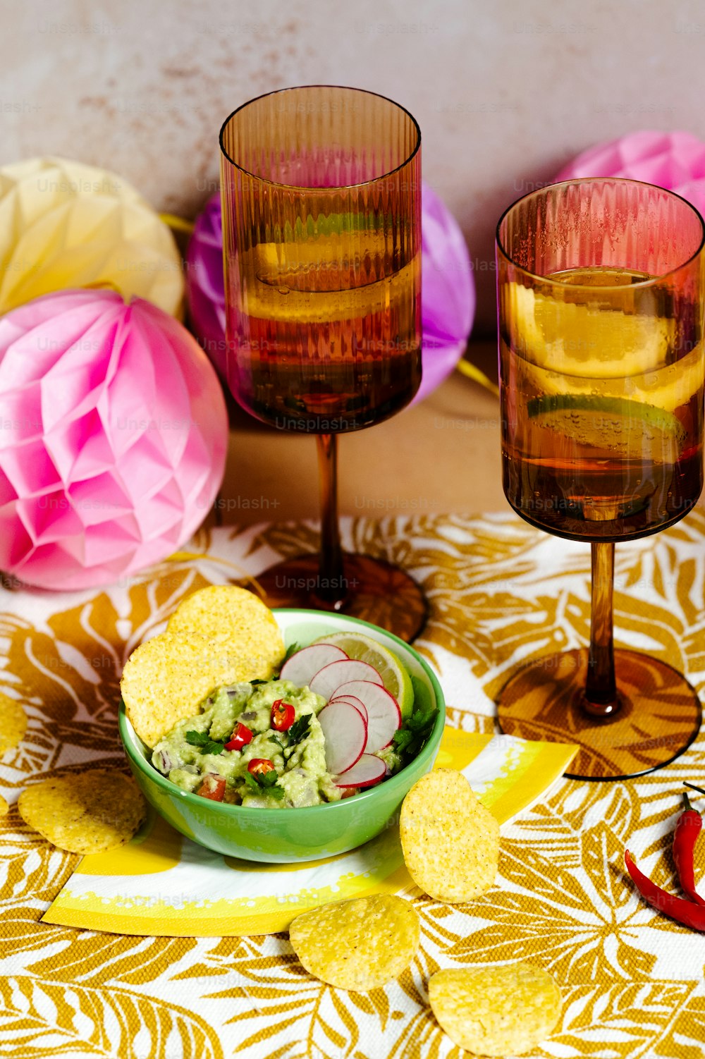 a bowl of guacamole next to two glasses