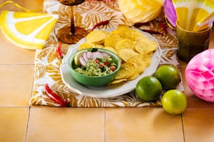 a plate of chips, guacamole, and limes on a table