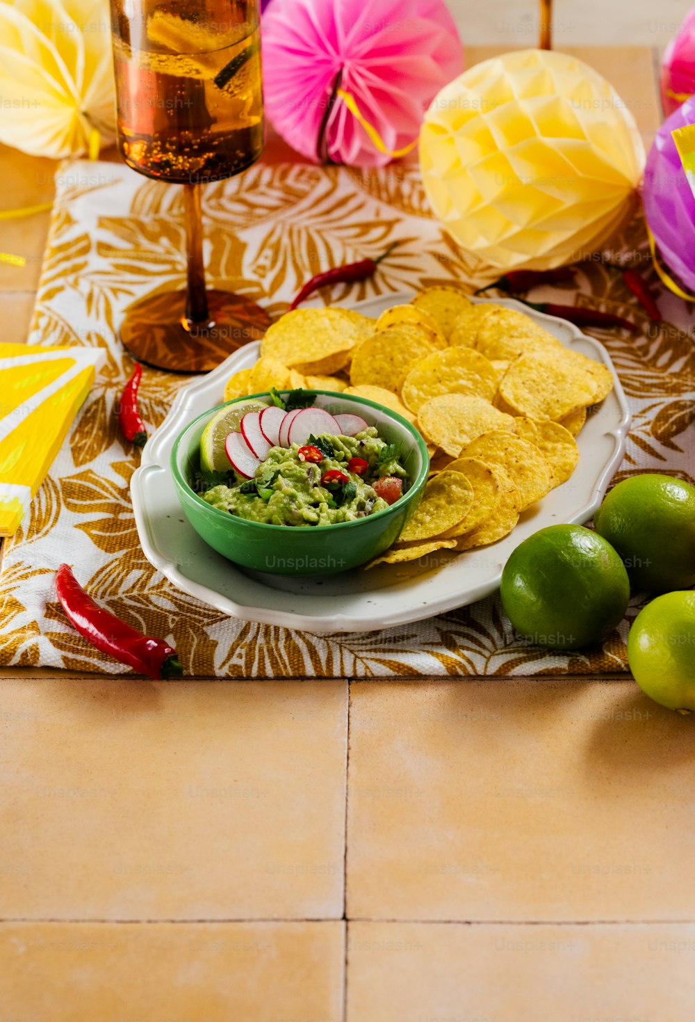 a plate of guacamole, tortilla chips, and limes