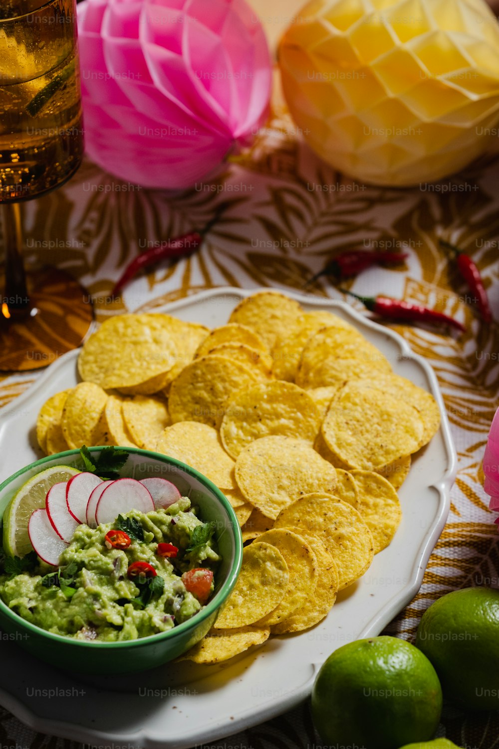 a plate of chips, guacamole, and radishes on a