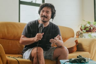 Ein Mann sitzt auf einer Couch und hält ein Mikrofon in der Hand