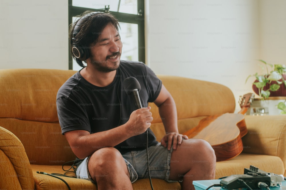 a man sitting on a couch holding a microphone