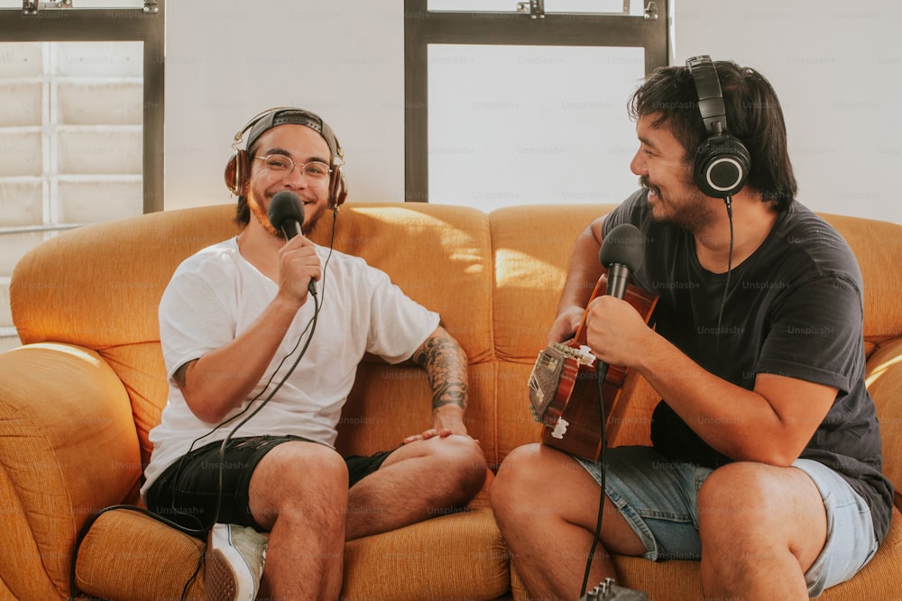 two men sitting on a couch with headphones on