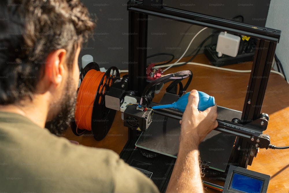 한 남자가 3D 프린터에서 작업하고 있다