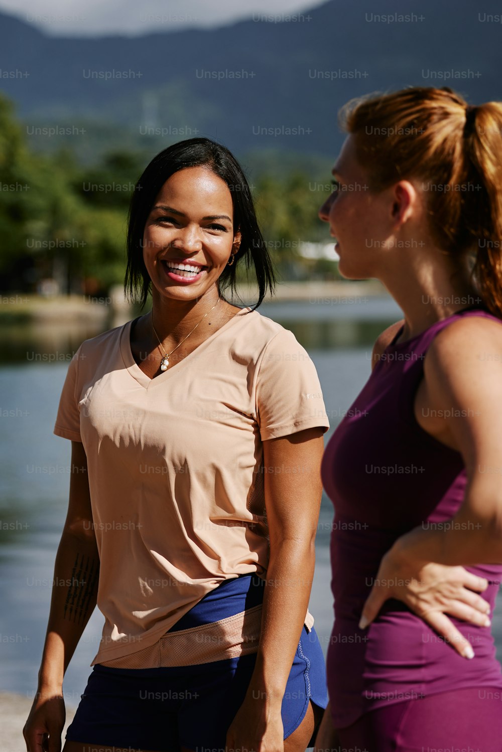a woman standing next to another woman near a body of water