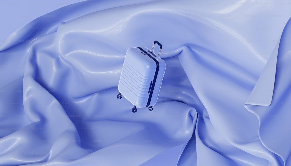 a white piece of luggage sitting on top of a blue cloth