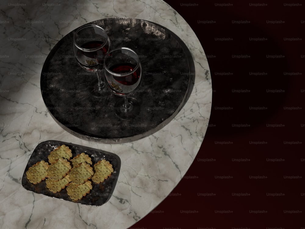 um prato de biscoitos e dois copos de vinho em uma mesa de mármore