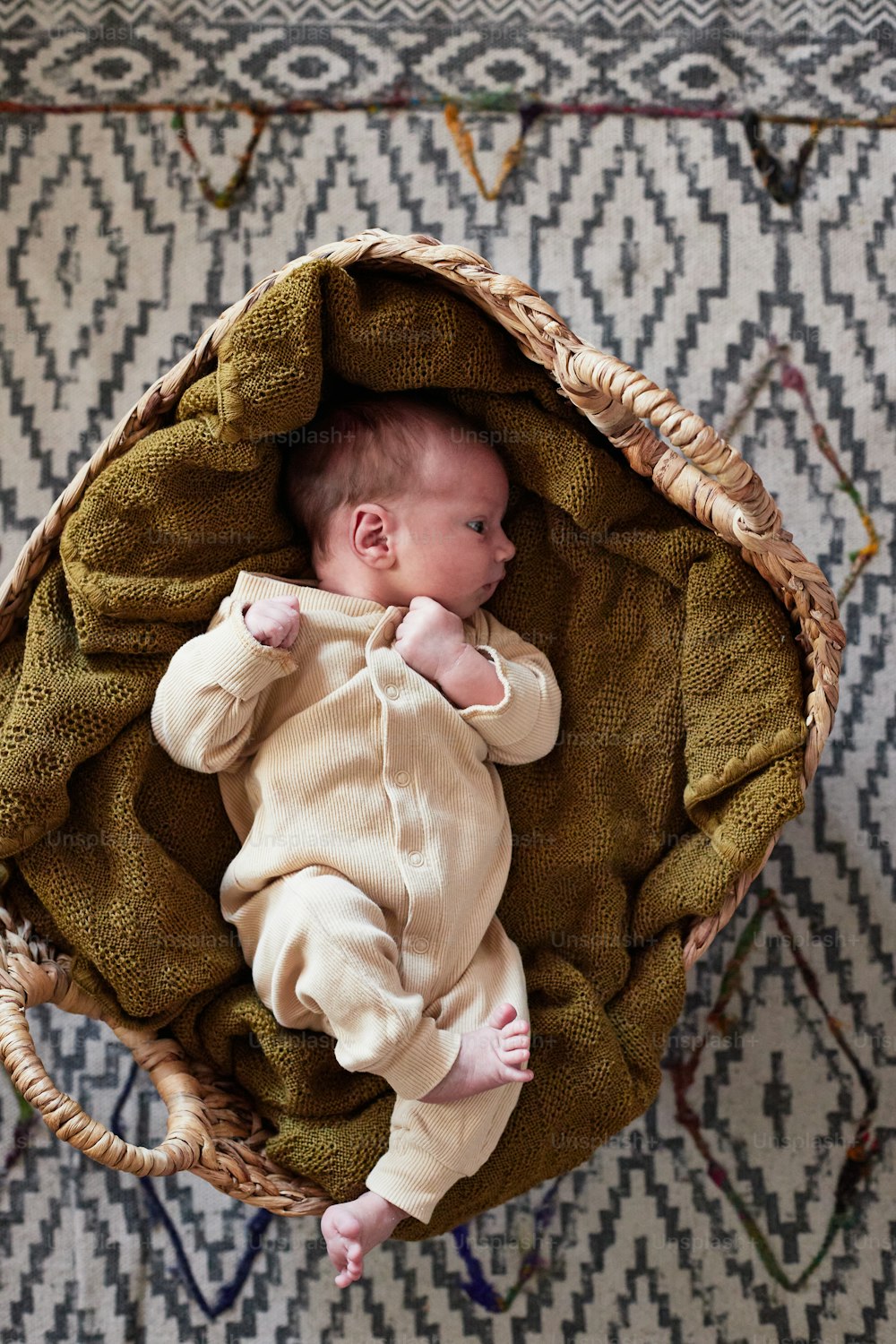 a baby laying in a basket on a rug