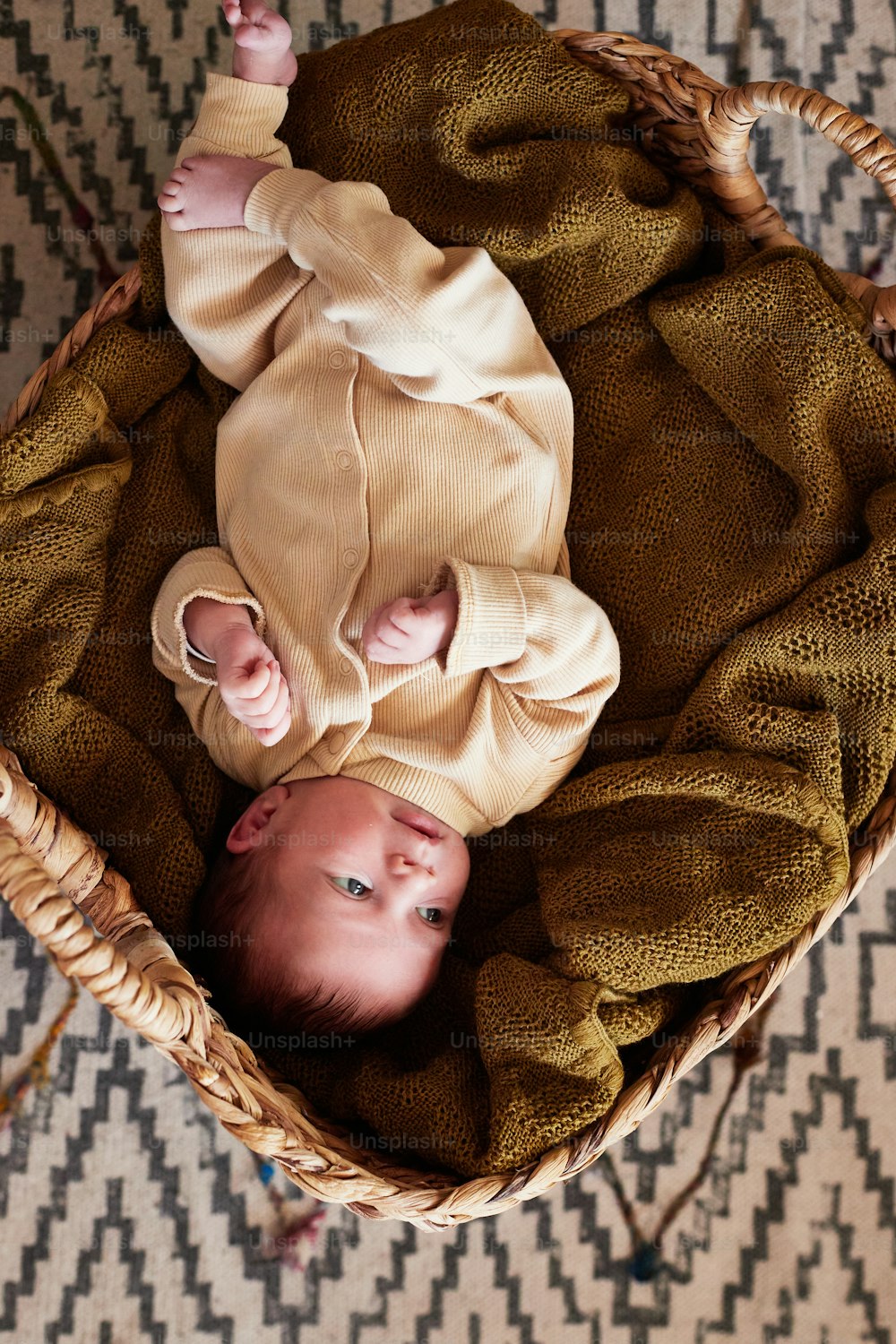 양탄자 위의 바구니에 누워 있는 두 아기
