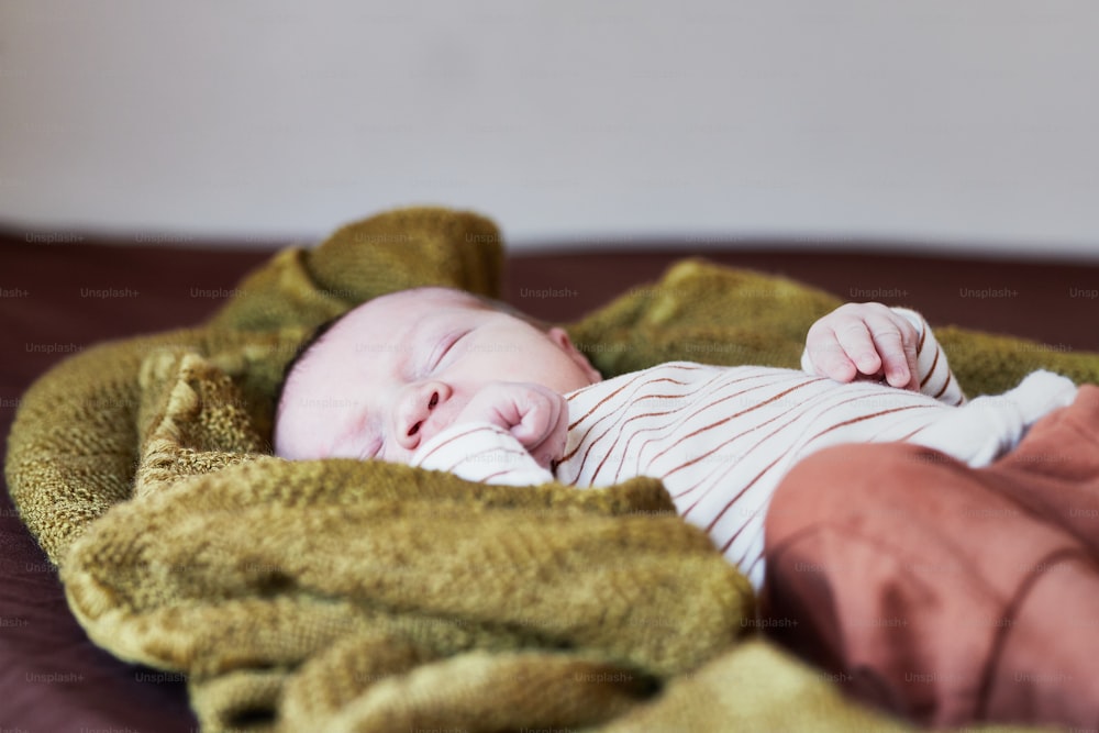 Un bebé acostado encima de una manta encima de una cama