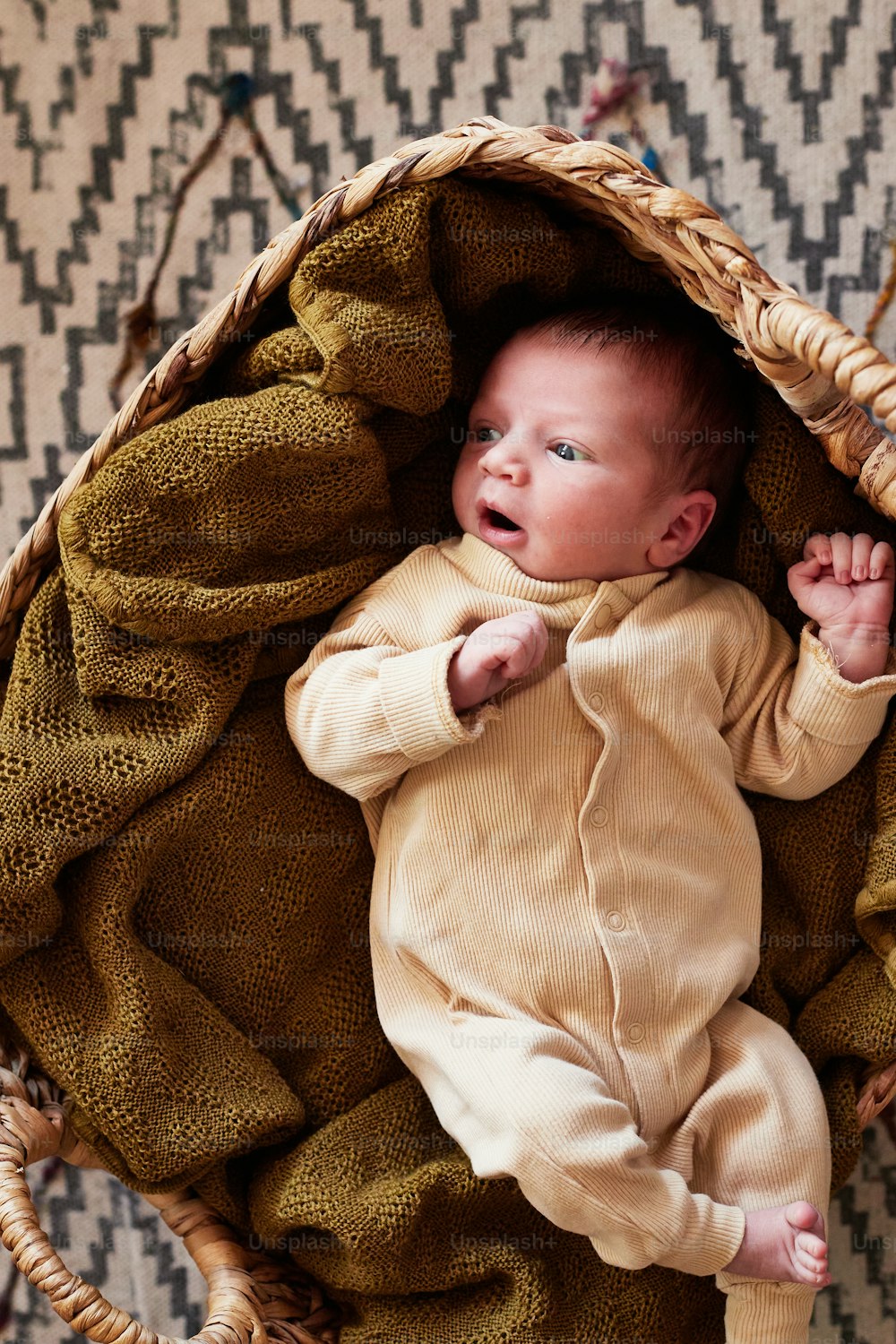 um bebê deitado em uma cesta com um cobertor
