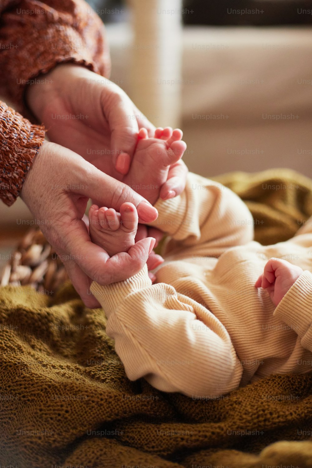 Una persona sosteniendo la mano de un bebé sobre una manta