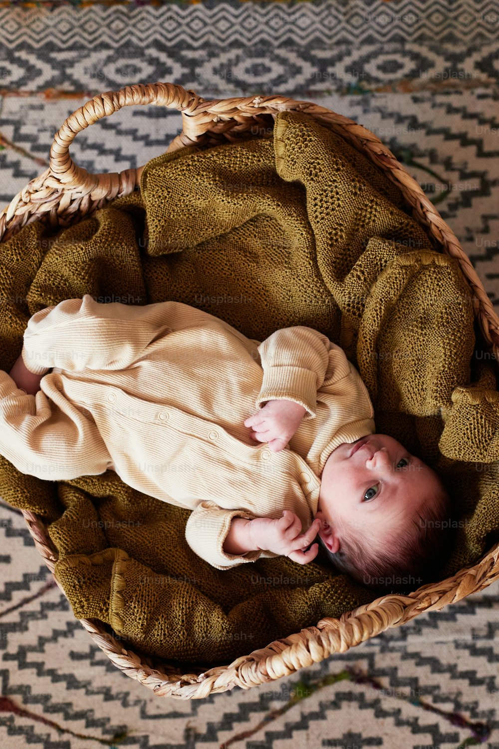 a baby laying in a basket on a rug