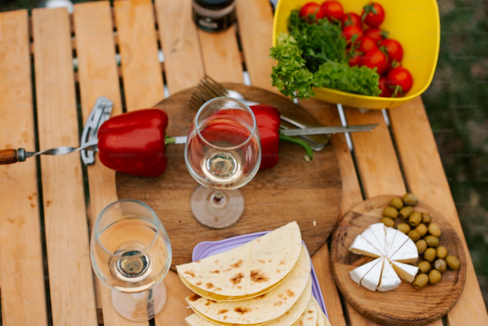 a wooden table topped with plates of food and glasses of wine