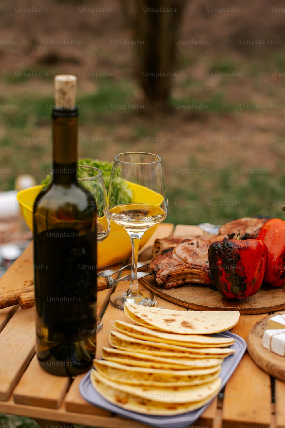 a wooden table topped with plates of food and a bottle of wine