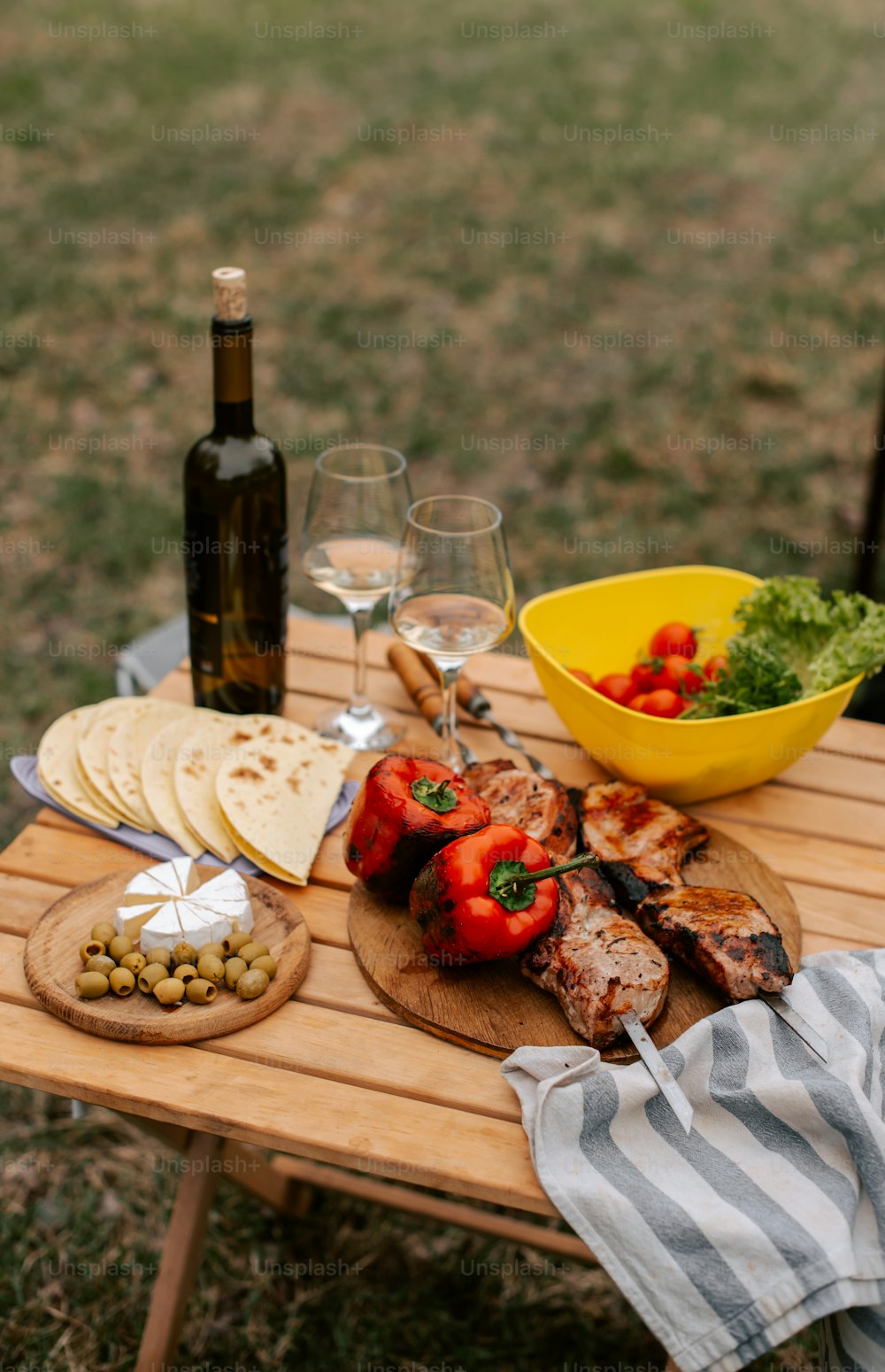 a wooden table topped with a plate of food and wine