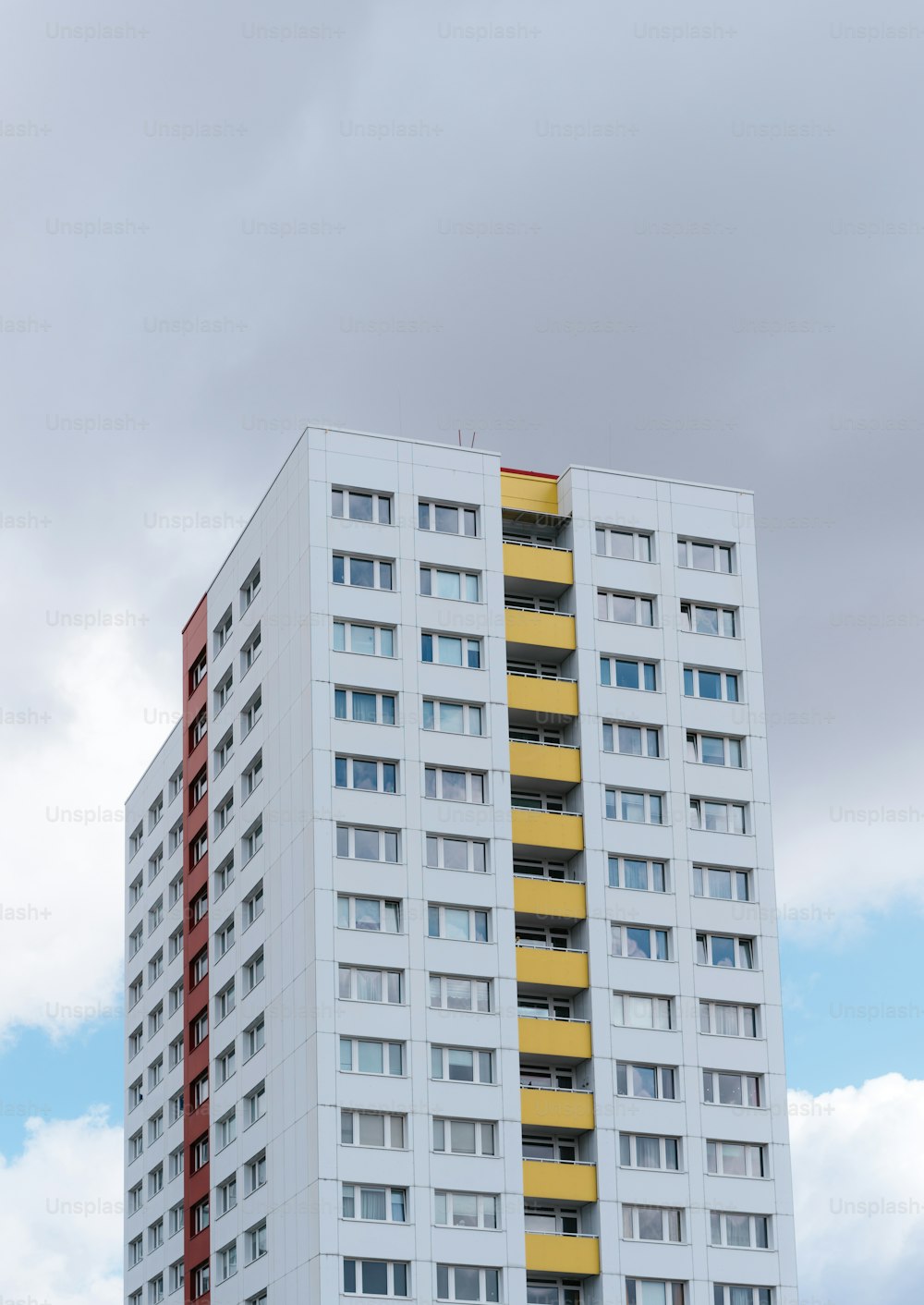 a tall white and yellow building on a cloudy day