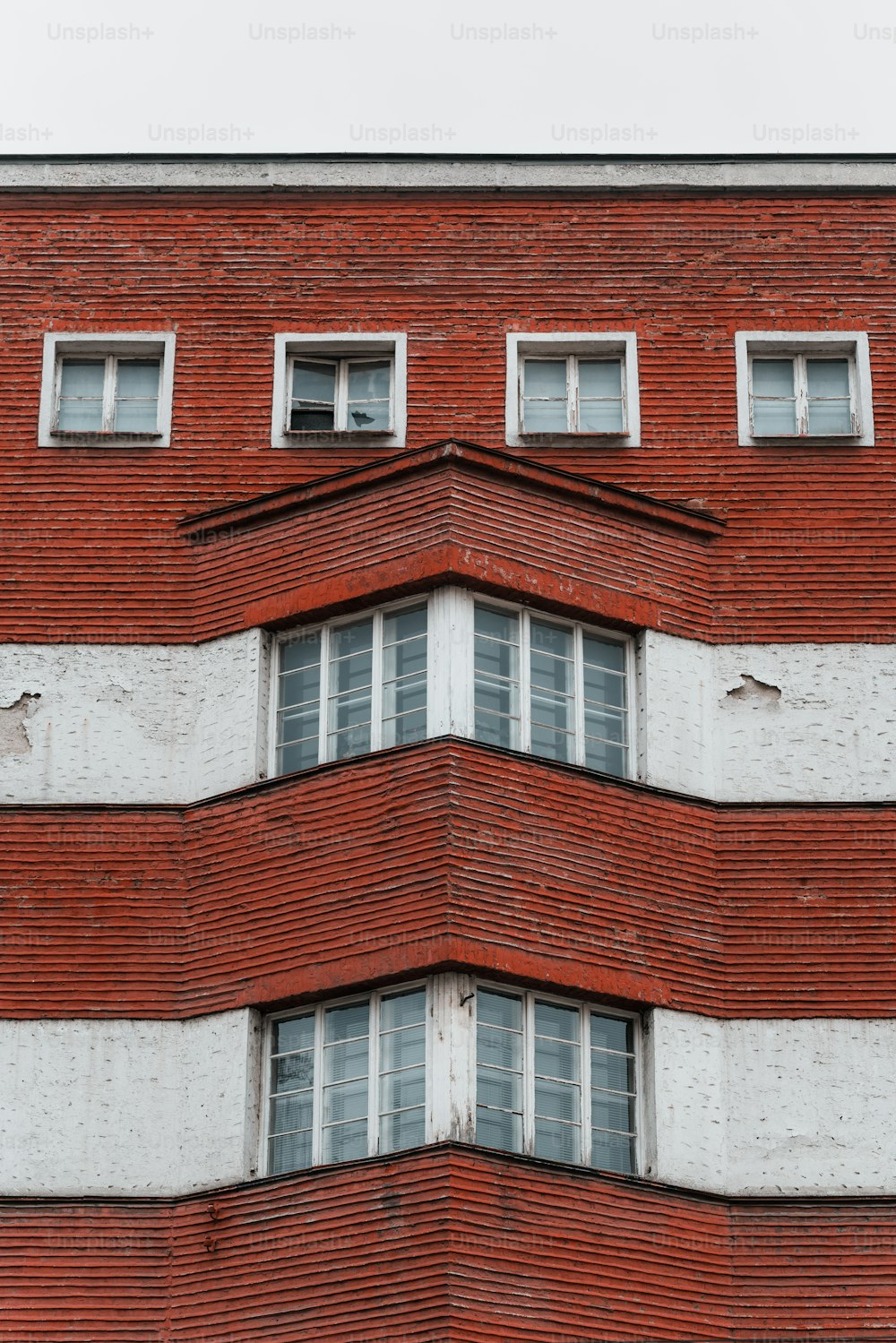 Un edificio de ladrillo rojo con ventanas blancas y un reloj