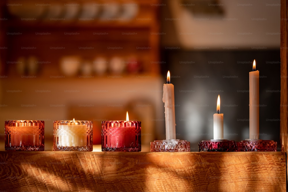 a row of lit candles sitting on top of a wooden table