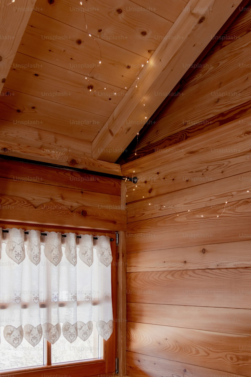 a bedroom with wood walls and white curtains