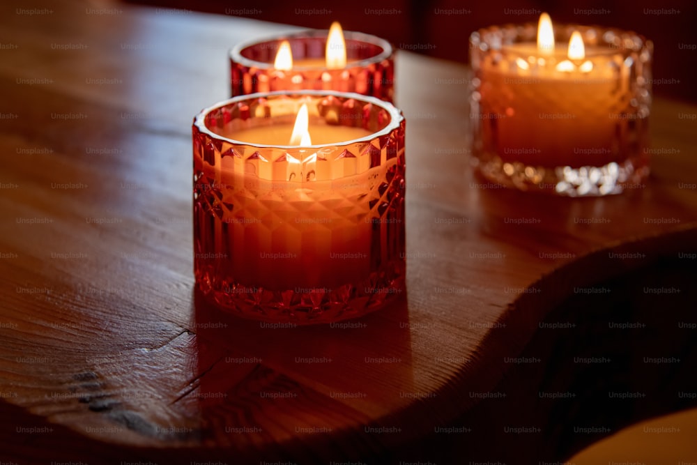 três velas acesas sentadas em uma mesa de madeira