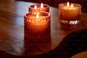 Tres velas encendidas sentadas sobre una mesa de madera