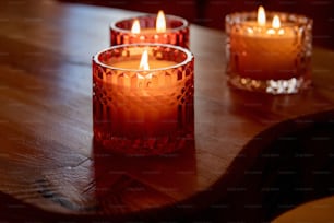 three lit candles sitting on a wooden table