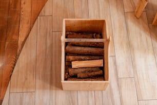 uma caixa de madeira cheia de troncos em cima de um piso de madeira