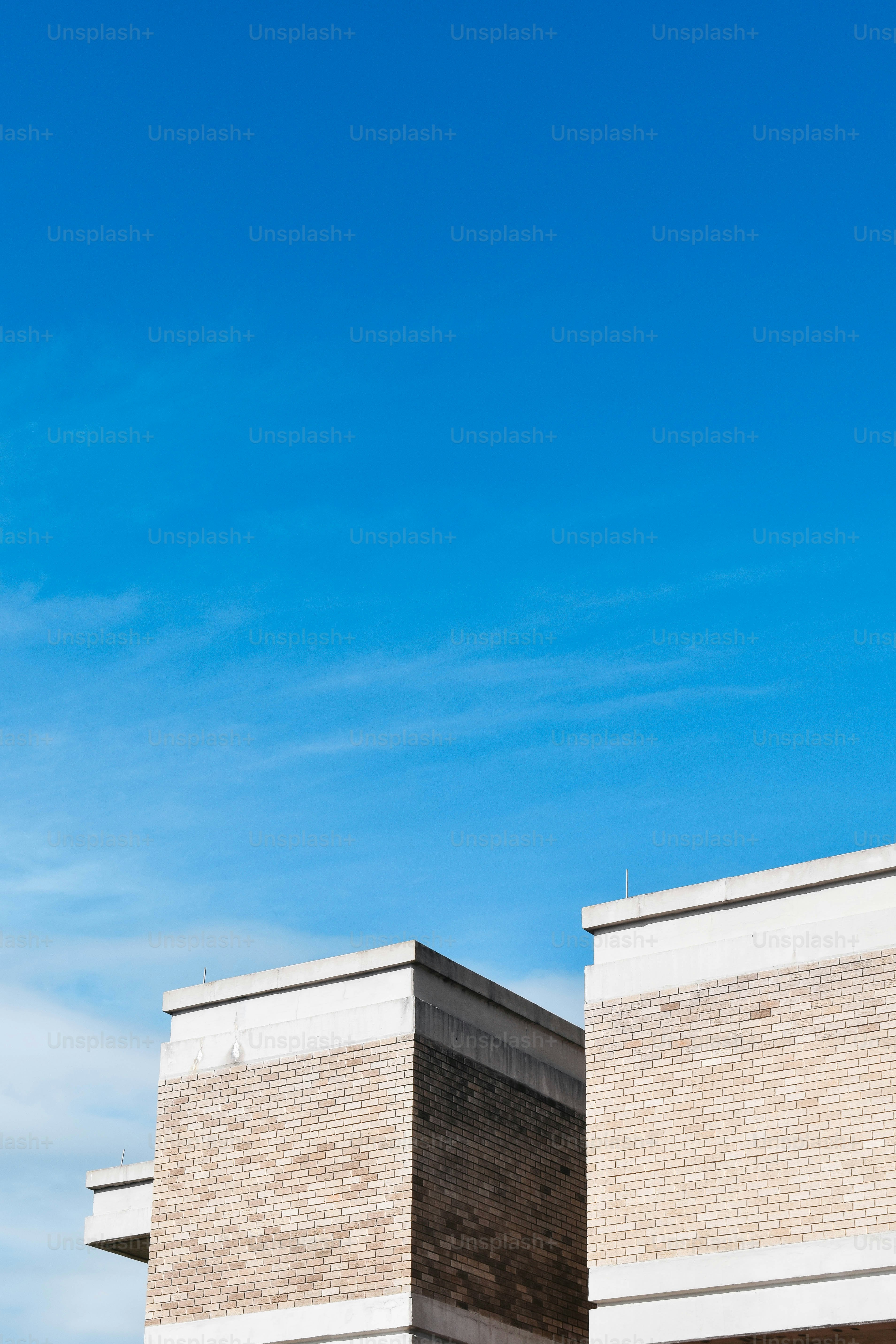 an airplane flying over a brick building under a blue sky