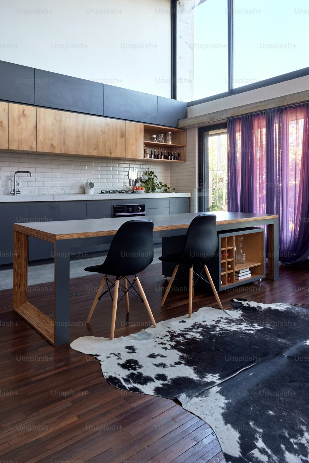 uma área de cozinha com uma mesa, cadeiras e um tapete de couro de vaca